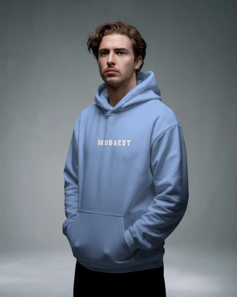 Man wearing a light blue hoodie with 'MODAEST' text on a gray background